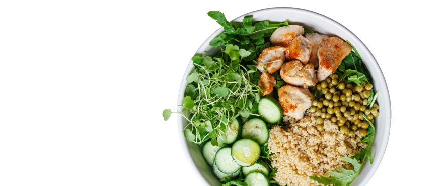 Miska z kolorowym, zdrowym posiłkiem: grillowany kurczak, zielony groszek, komosa ryżowa, plastry ogórka, rukola i kiełki. Składniki ułożone są warstwowo, tworząc apetyczną kompozycję.