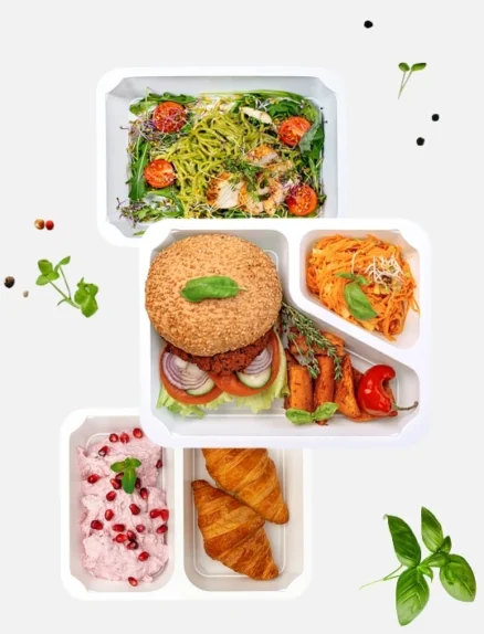 Trzy pojemniki z różnymi daniami. W górnym pojemniku znajduje się sałatka z zielonym makaronem, grillowanym kurczakiem i pomidorkami koktajlowymi. W środkowym pojemniku burger z warzywami, pieczone marchewki i surówka z marchwi. W dolnym pojemniku dwa rogaliki i deser z różowym kremem oraz pestkami granatu.